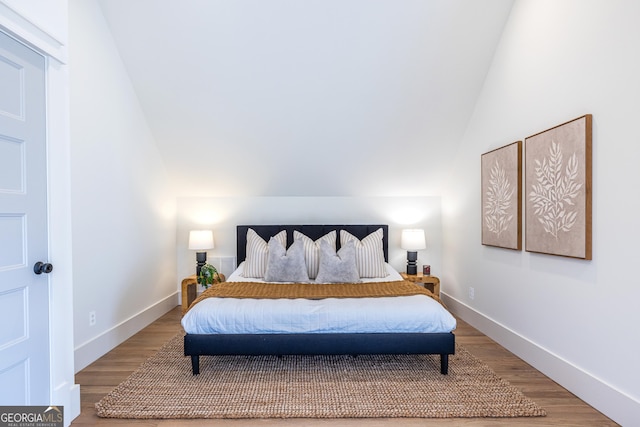 bedroom with lofted ceiling and wood-type flooring