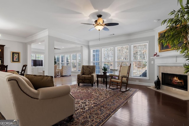 living room with a high end fireplace, ceiling fan, crown molding, and dark hardwood / wood-style floors