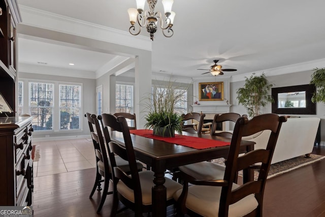 dining area featuring ceiling fan with notable chandelier, crown molding, and dark wood-type flooring