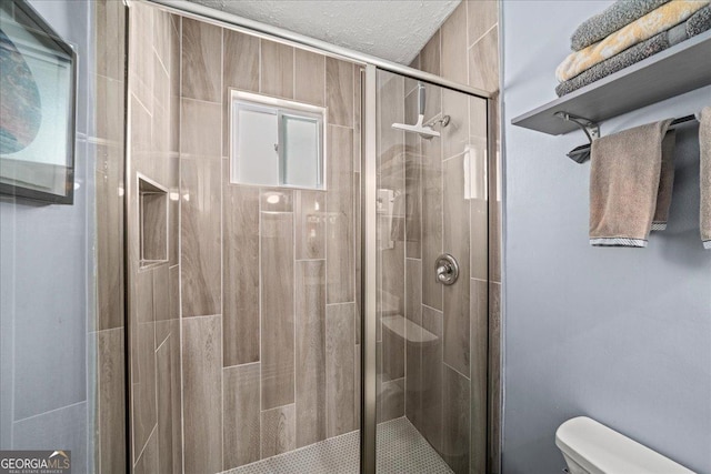 bathroom with toilet, a textured ceiling, and an enclosed shower