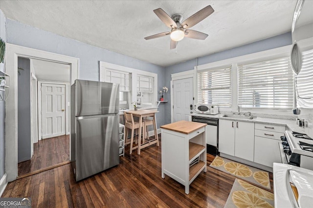 kitchen featuring a center island, white cabinetry, stainless steel appliances, sink, and butcher block countertops