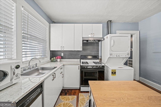 kitchen with white cabinetry, backsplash, white gas stove, stacked washing maching and dryer, and sink