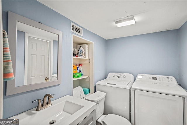 bathroom featuring toilet, sink, and washing machine and clothes dryer