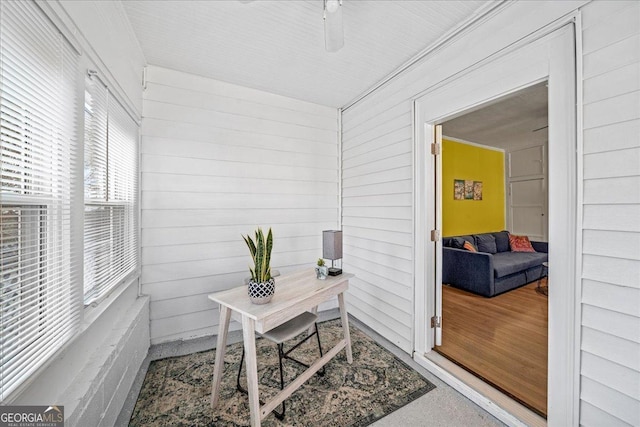 office space with ceiling fan and wooden walls