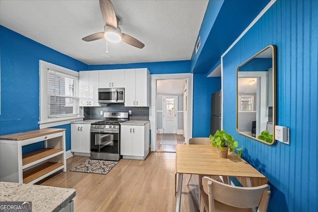 kitchen with ceiling fan, tasteful backsplash, white cabinetry, light wood-type flooring, and appliances with stainless steel finishes