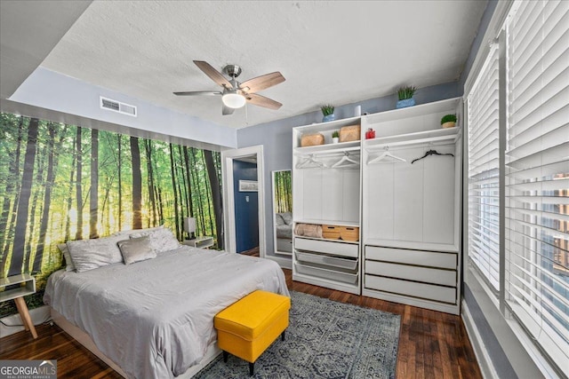 bedroom with ceiling fan, a textured ceiling, dark hardwood / wood-style flooring, and a closet