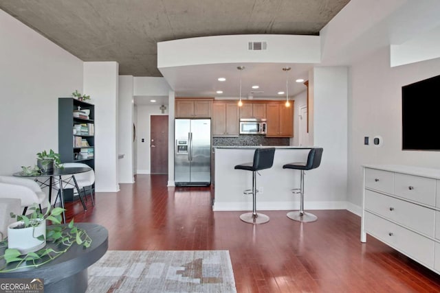 kitchen with stainless steel appliances, pendant lighting, backsplash, a breakfast bar, and dark wood-type flooring