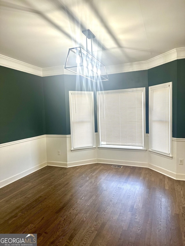 unfurnished dining area featuring dark wood-type flooring and crown molding