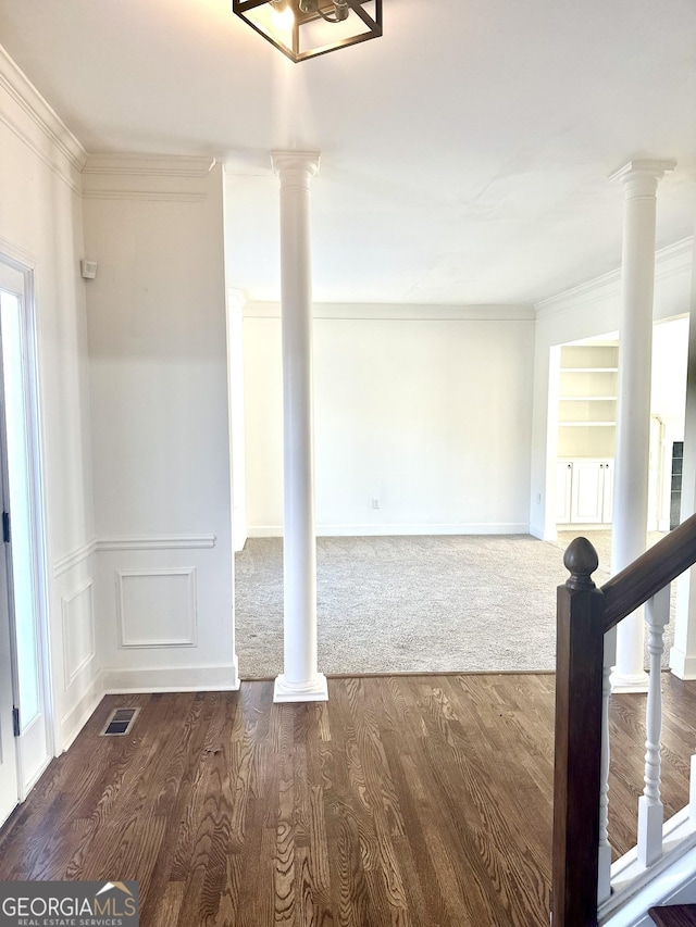 unfurnished room featuring ornamental molding, built in shelves, and dark hardwood / wood-style floors