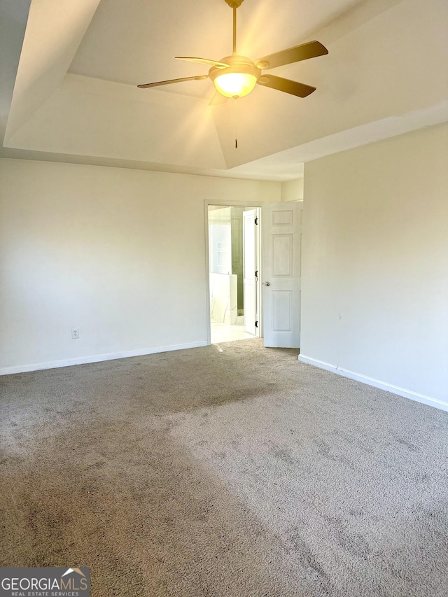 spare room with carpet flooring, ceiling fan, and a tray ceiling