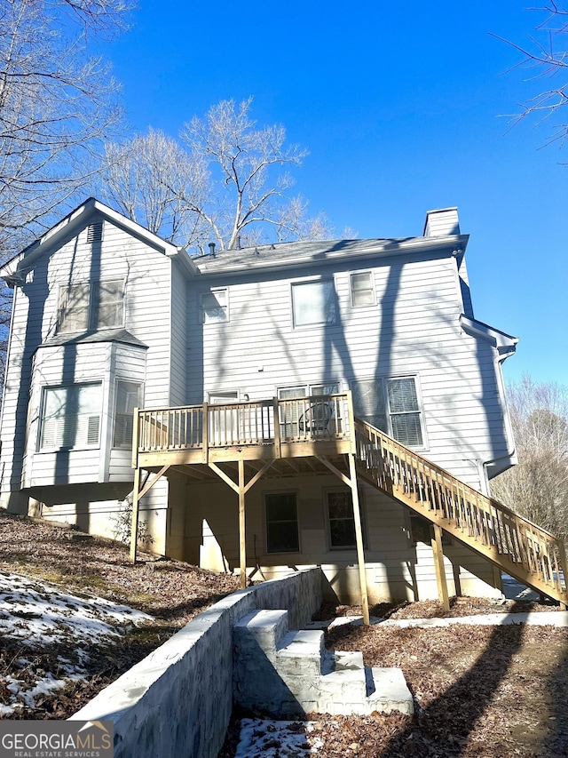 snow covered rear of property with a deck