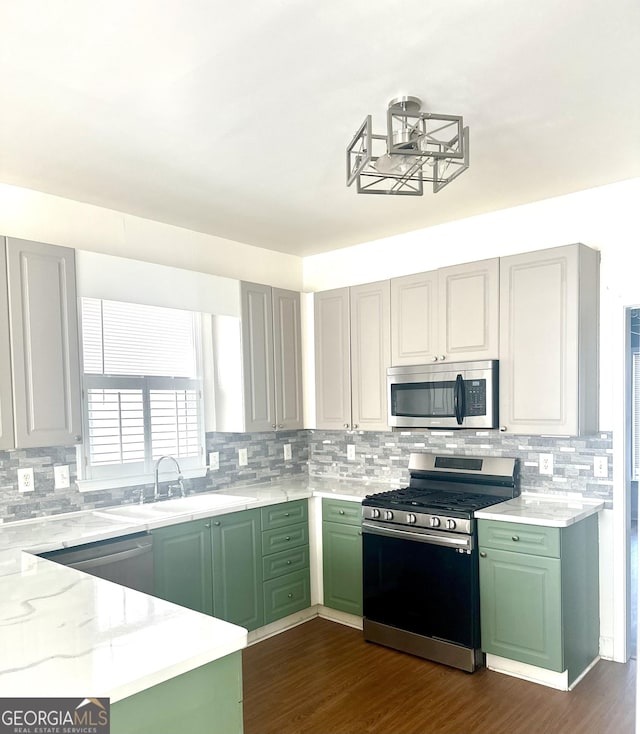 kitchen with stainless steel appliances, light stone countertops, dark hardwood / wood-style flooring, green cabinets, and sink