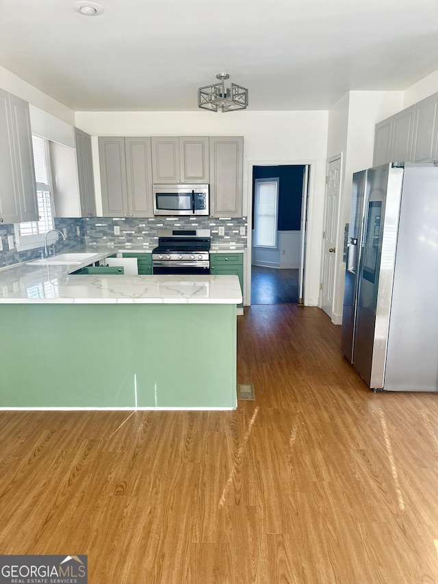 kitchen with stainless steel appliances, tasteful backsplash, gray cabinetry, and kitchen peninsula