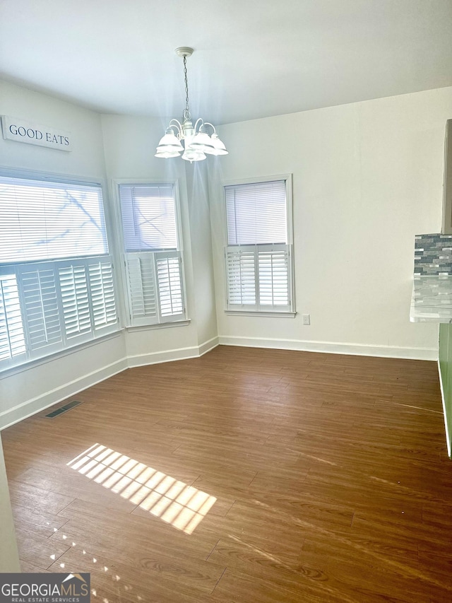 unfurnished dining area with dark hardwood / wood-style flooring and a chandelier