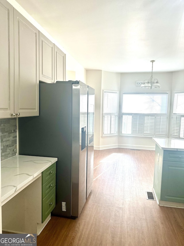 kitchen with a chandelier, light wood-type flooring, green cabinetry, decorative light fixtures, and tasteful backsplash