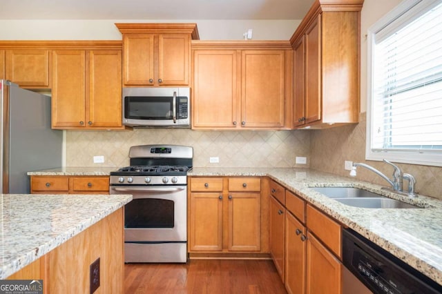 kitchen with sink, stainless steel appliances, backsplash, and light stone countertops