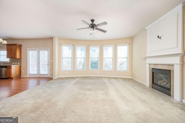 unfurnished living room with a tiled fireplace, ceiling fan, and light carpet