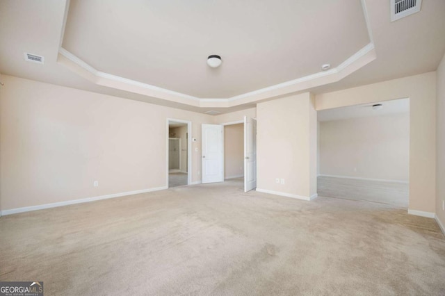 carpeted spare room with a tray ceiling and crown molding