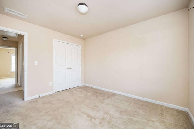 unfurnished bedroom featuring light colored carpet and a closet