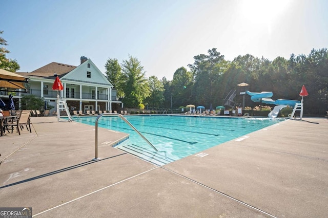 view of pool featuring a water slide and a patio