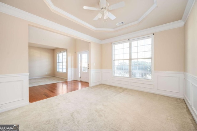 carpeted empty room featuring ceiling fan, a tray ceiling, and crown molding