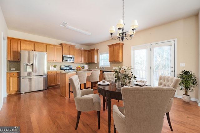 dining space with dark wood-type flooring, a notable chandelier, and sink