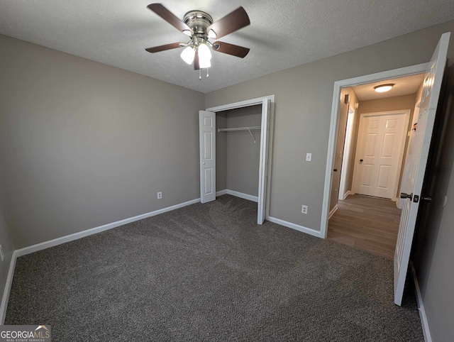 unfurnished bedroom featuring a closet, ceiling fan, a textured ceiling, and dark colored carpet