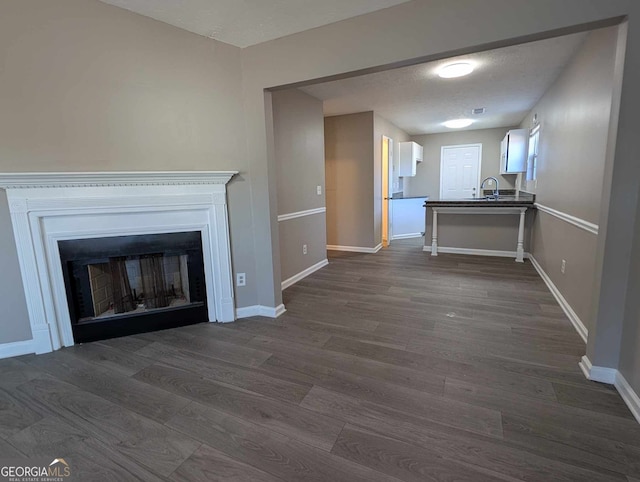 unfurnished living room featuring a textured ceiling and dark hardwood / wood-style floors