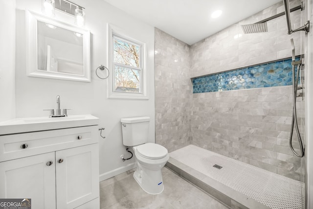 bathroom with tiled shower, vanity, and toilet