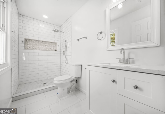 bathroom with toilet, a tile shower, vanity, and tile patterned floors