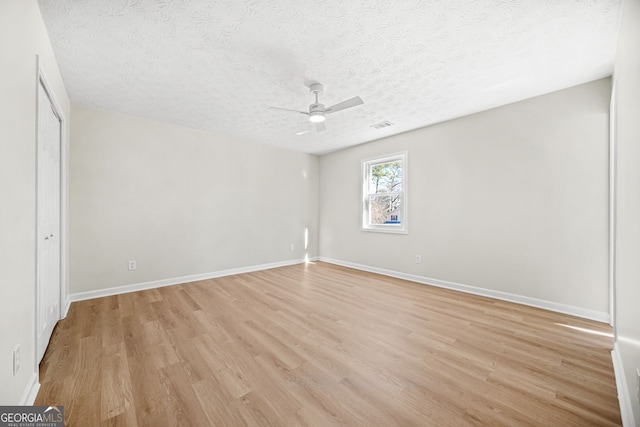 spare room with a textured ceiling, ceiling fan, and light wood-type flooring