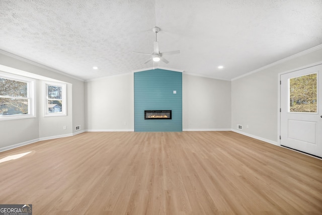 unfurnished living room featuring vaulted ceiling, crown molding, a fireplace, a textured ceiling, and light hardwood / wood-style flooring