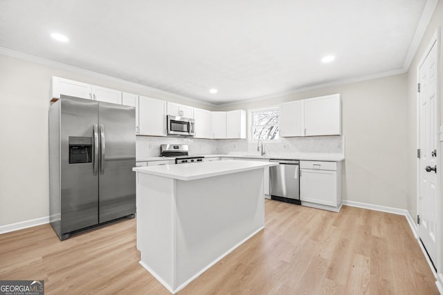 kitchen featuring stainless steel appliances, white cabinets, a center island, light hardwood / wood-style floors, and crown molding