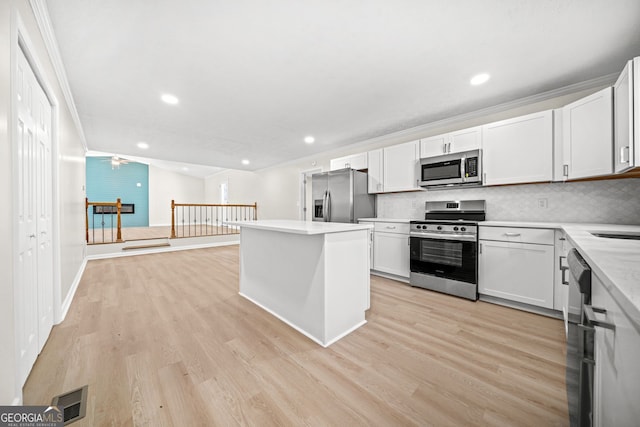 kitchen with stainless steel appliances, white cabinets, ceiling fan, decorative backsplash, and a kitchen island