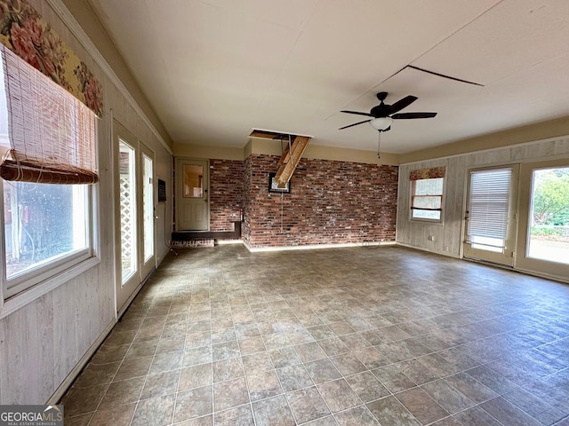 unfurnished living room with brick wall and ceiling fan