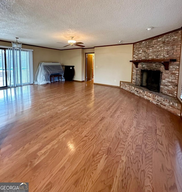 unfurnished living room featuring a textured ceiling, ceiling fan, a brick fireplace, and hardwood / wood-style flooring