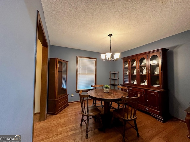 dining room with hardwood / wood-style floors, a textured ceiling, and a chandelier