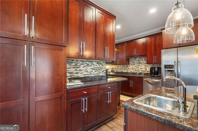 kitchen featuring dark stone countertops, stainless steel appliances, sink, decorative light fixtures, and backsplash