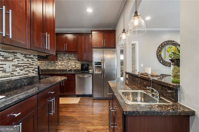 kitchen with sink, stainless steel appliances, ornamental molding, and decorative light fixtures