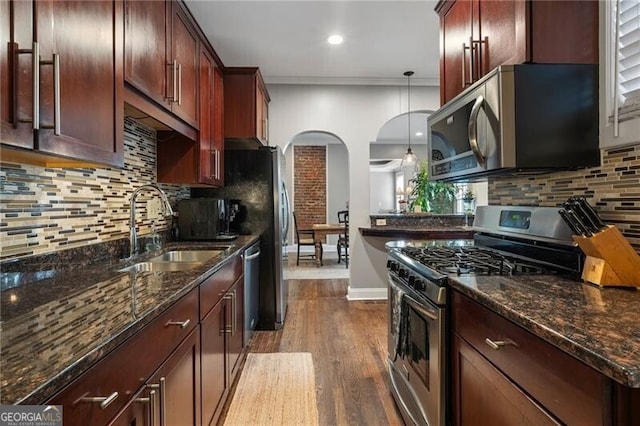 kitchen featuring dark wood-type flooring, pendant lighting, stainless steel appliances, crown molding, and sink