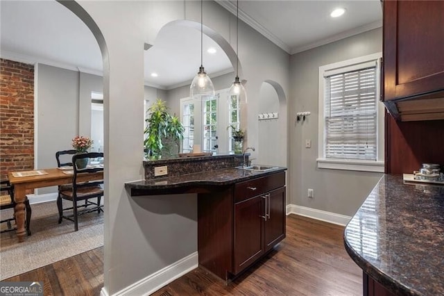 kitchen with hanging light fixtures, plenty of natural light, dark stone counters, and dark hardwood / wood-style floors