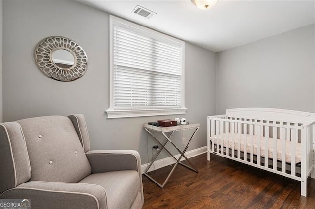 bedroom featuring a crib and dark wood-type flooring