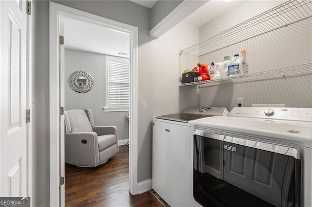 clothes washing area featuring washing machine and clothes dryer and dark hardwood / wood-style floors