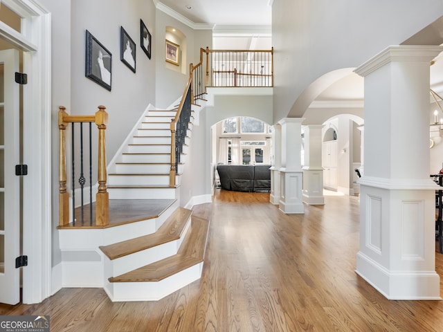 entrance foyer featuring ornamental molding, light hardwood / wood-style flooring, and ornate columns