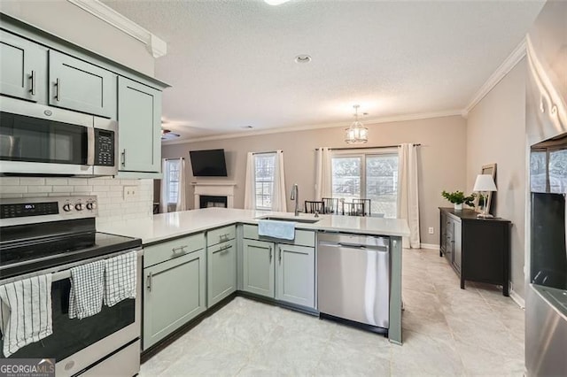 kitchen featuring appliances with stainless steel finishes, kitchen peninsula, green cabinets, sink, and an inviting chandelier