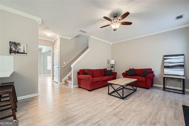 living room with a textured ceiling, light wood-type flooring, ceiling fan, and crown molding