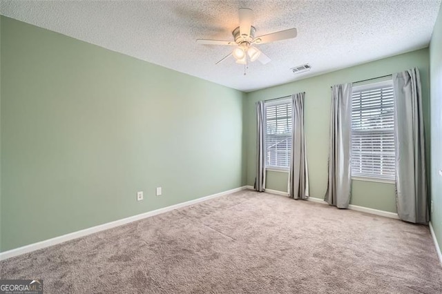 carpeted spare room featuring a textured ceiling and ceiling fan