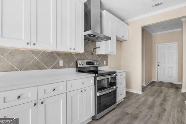 kitchen featuring double oven range, wall chimney range hood, light hardwood / wood-style floors, tasteful backsplash, and white cabinetry