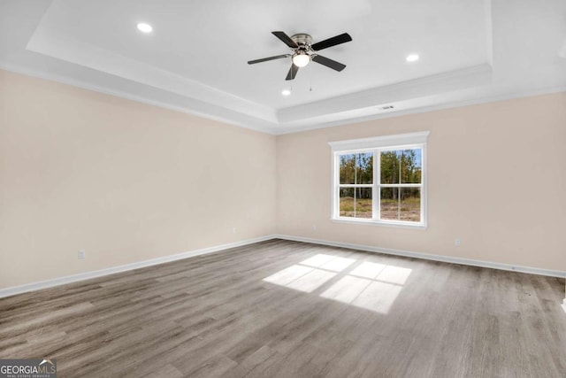 spare room with a raised ceiling, light wood-type flooring, ceiling fan, and ornamental molding