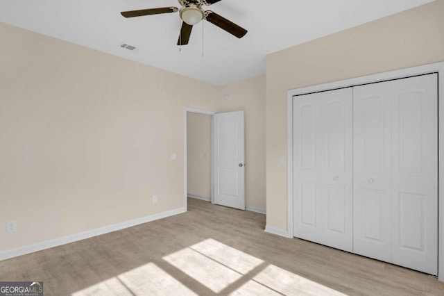 unfurnished bedroom with light wood-type flooring, ceiling fan, and a closet